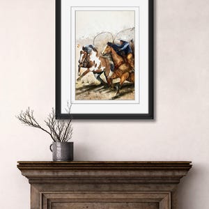 May include: Watercolor painting of two horses running, ridden by cowboys. The horses are brown and white, and the cowboys are wearing blue shirts and hats. The artwork is framed in a black frame and displayed on a wooden mantel.