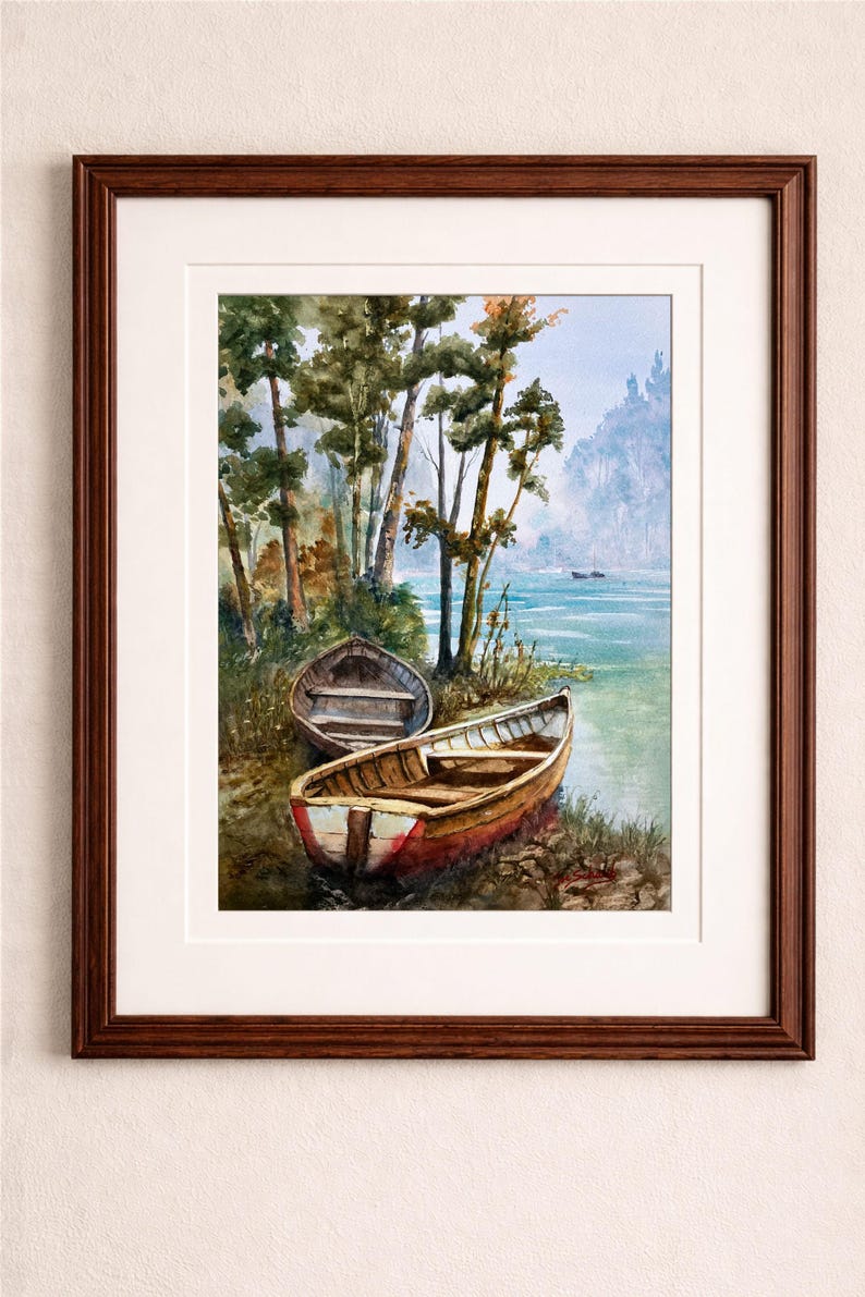 Op de afbeelding: Aquarel schilderij van een serene meer sc&egrave;ne met drie houten roeiboten aan de oever. De boten zijn bruin en rood, met bomen en een mistige berg op de achtergrond. Het kunstwerk is ingelijst in een donkerbruine houten lijst.