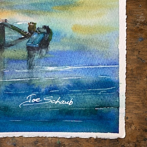Puede incluir: Una pintura de acuarela sobre papel texturizado que muestra un paisaje marino azul y verde con una estructura de muelle oscura que se extiende hacia el agua. La obra presenta una firma en tinta blanca que dice Joe Schaub en la esquina inferior izquierda.