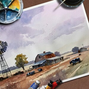 May include: Watercolor painting of a rural farm scene with a barn, windmill, and cows grazing in a field. The artwork features a muted color palette with shades of brown, blue, and purple. Paint tubes and a palette are visible.
