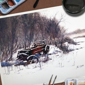 May include: Watercolour painting depicting a vintage truck in a snowy scene. The truck is rusty red and brown, set amongst bare trees and snow. Paintbrushes, a watercolour palette, and a paint tube are in the foreground.