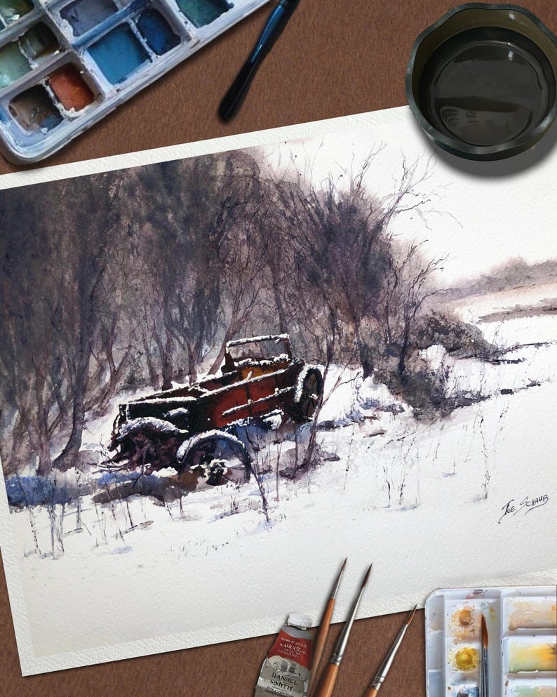May include: Watercolour painting depicting a vintage truck in a snowy scene. The truck is rusty red and brown, set amongst bare trees and snow. Paintbrushes, a watercolour palette, and a paint tube are in the foreground.