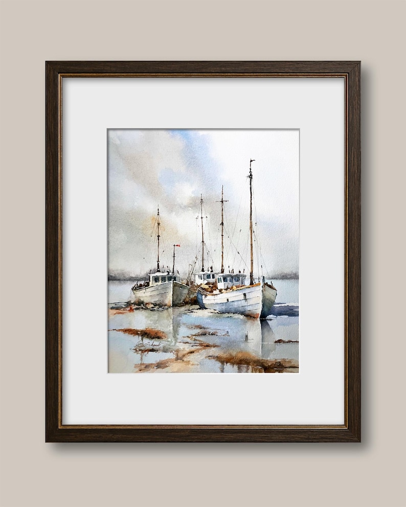 May include: A framed watercolor painting depicting three white fishing boats moored in shallow water. The scene features tall masts, soft blue and grey sky tones, and brown reflections on the water surface, all enclosed in a dark brown frame.