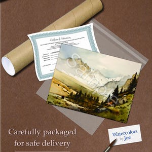 May include: A watercolor painting of a mountain landscape with a certificate of authenticity, a rolled-up tube, and a paintbrush. The painting is in a clear plastic sleeve. The text "Sample" is visible on the painting. The painting is labeled "Watercolors By Joe".
