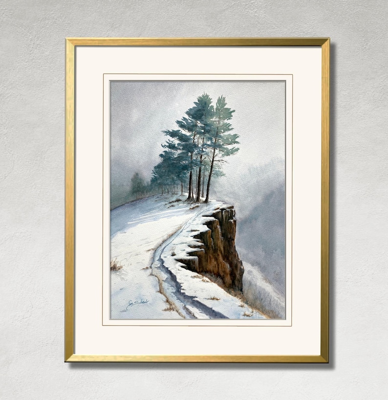K&ouml;nnte beinhalten: Ein gerahmtes Aquarellgem&auml;lde zeigt eine schneebedeckte Klippe mit immergr&uuml;nen B&auml;umen. Das Kunstwerk zeigt einen Pfad, der zum Rand f&uuml;hrt, mit einem goldfarbenen Rahmen und einem wei&szlig;en Passepartout. Das Gem&auml;lde erinnert an eine ruhige Winterlandschaft.