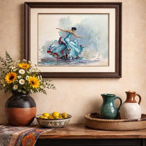 May include: A framed watercolor painting of a flamenco dancer in a flowing blue dress with red accents. The artwork hangs above a table with a vase of sunflowers, a bowl of lemons, and decorative pitchers.