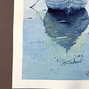 May include: Watercolor painting of two blue rowboats reflected in the water. The artwork features a serene scene with soft blue and white hues, and the artist's signature, "Joe Schaub", is visible in the lower right corner.