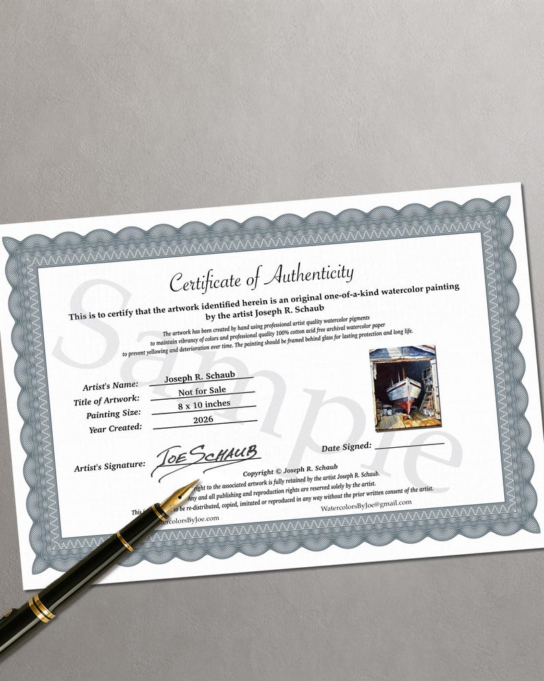 May include: A white Certificate of Authenticity document with a grey decorative border, featuring the text Certificate of Authenticity, artist Joseph R. Schaub, and a small watercolor painting of a boat. A black fountain pen rests on the document.