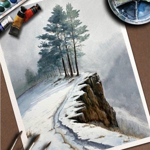 K&ouml;nnte beinhalten: Aquarellmalerei einer schneebedeckten Landschaft mit einem Weg, der zu einer Klippe f&uuml;hrt. Mehrere hohe B&auml;ume stehen am Rand der Klippe. Die Malerei verwendet Blau-, Grau- und Braunt&ouml;ne. Farbtuben, Pinsel und eine Palette sind sichtbar.