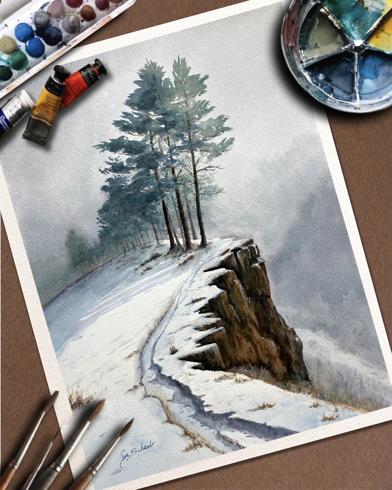 K&ouml;nnte beinhalten: Aquarellmalerei einer schneebedeckten Landschaft mit einem Weg, der zu einer Klippe f&uuml;hrt. Mehrere hohe B&auml;ume stehen am Rand der Klippe. Die Malerei verwendet Blau-, Grau- und Braunt&ouml;ne. Farbtuben, Pinsel und eine Palette sind sichtbar.