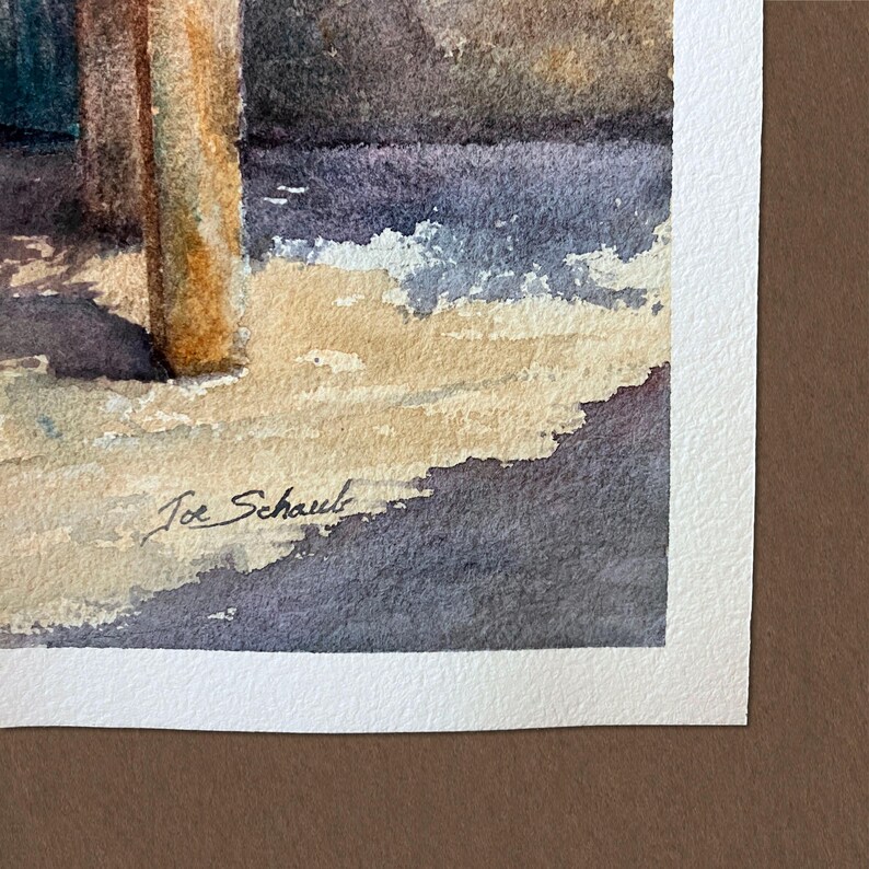 May include: A watercolour painting on textured white paper featuring a vertical tan pillar and dark purple shadows cast across a light beige ground. The artist's signature, Joe Schaub, is written in black ink in the lower left corner of the artwork.