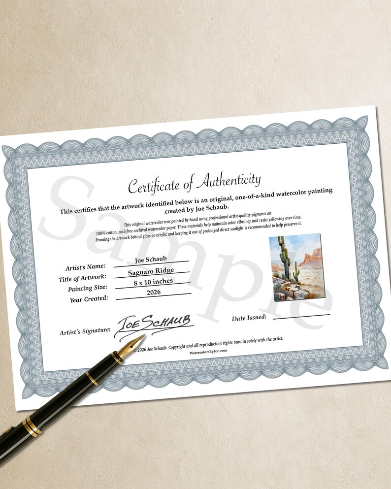May include: A Certificate of Authenticity for a watercolor painting titled Saguaro Ridge by Joe Schaub, dated 2026, measuring 8 x 10 inches. The document features a blue decorative border, a small image of the artwork, and a black fountain pen.
