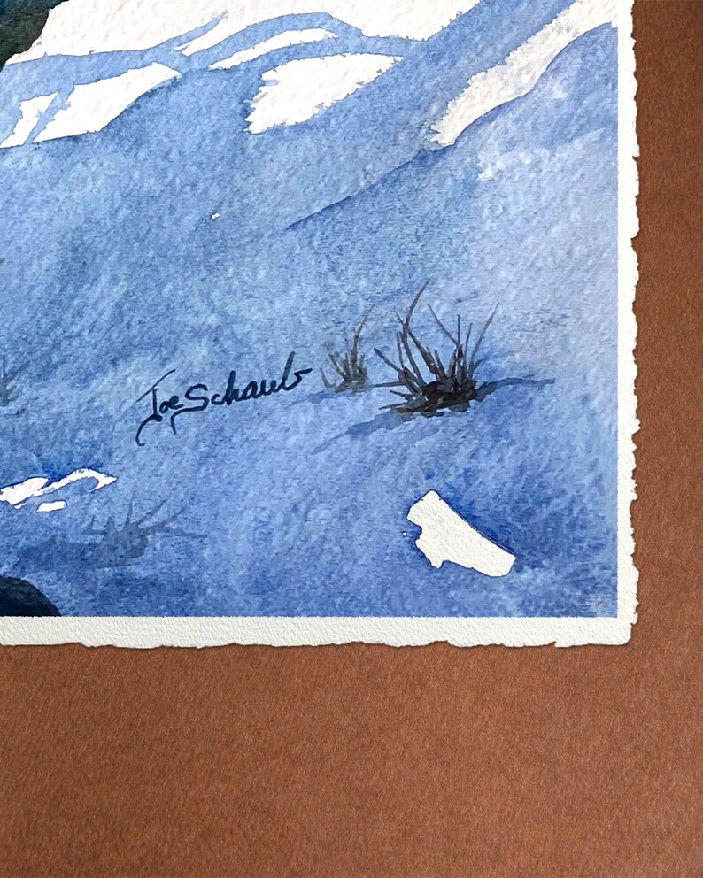 May include: Watercolor painting of a mountain landscape in shades of blue and white. The artwork features a signature in the lower left corner and a few tufts of grass. The painting is mounted on a white paper with a torn edge.