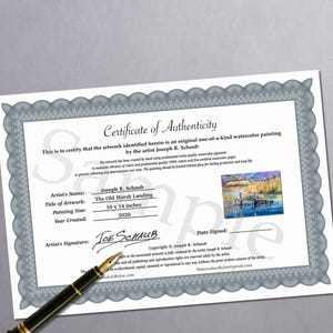 Puede incluir: Un certificado de autenticidad para una pintura de acuarela titulada The Old Marsh Landing del artista Joseph R. Schaub. El documento presenta un borde decorativo gris, una peque&ntilde;a imagen de la pintura y el texto 10 x 14 inches. Una pluma estilogr&aacute;fica negra descansa sobre el documento.