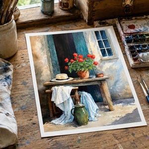 May include: A watercolour painting depicting a rustic wooden table and bench set against a textured wall. A terracotta pot with red geraniums, a straw hat, and a green ceramic pitcher are visible, with white fabric draped over the bench.