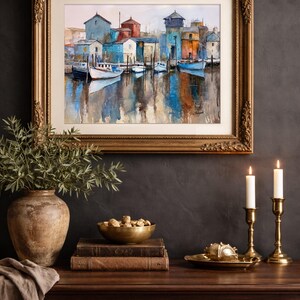 May include: A framed watercolor painting of a harbor scene with boats and buildings in shades of blue, orange, and white. The painting is displayed above a wooden cabinet with decorative items, including a vase, bowl, books, and candlesticks.
