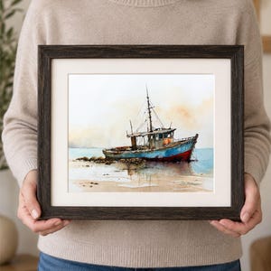 May include: A framed watercolor painting depicting a weathered fishing boat resting on a sandy shore. The vessel features a blue hull with a red bottom, a cabin, and a mast. The background shows a soft, hazy sky and calm water in muted tones.