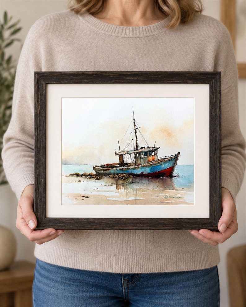 May include: A framed watercolor painting depicting a weathered fishing boat resting on a sandy shore. The vessel features a blue hull with a red bottom, a cabin, and a mast. The background shows a soft, hazy sky and calm water in muted tones.