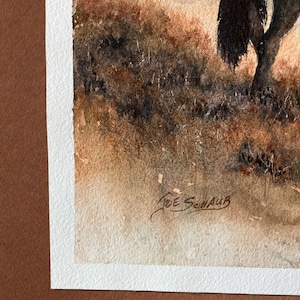 May include: Watercolor painting of a landscape with a tree and tall grass. The artwork is signed "Joe Schaub" in the lower right corner. The painting is framed with a white border and a brown mat.