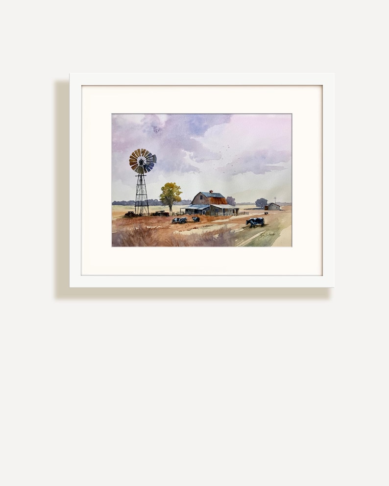 May include: Watercolor painting of a rural landscape featuring a windmill, barn, and fields under a cloudy sky. The artwork is framed in a white mat and frame, showcasing a serene farm scene with muted colors.