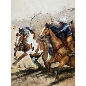 May include: Watercolor painting of a cowboy roping a horse. The painting features two horses, one brown and white, the other brown, with a cowboy in a blue jacket and white hat. The artwork has a rustic, western theme.