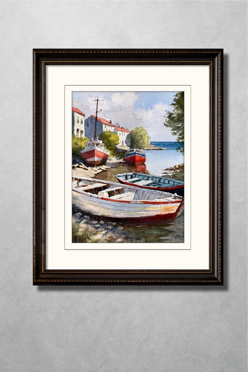 May include: Watercolor painting of several small boats resting on a shoreline. The boats are painted in red and white, with a few blue boats in the background. Buildings with red roofs and a blue sky complete the coastal scene, framed in a dark wood frame.