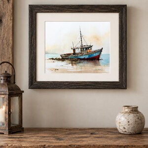 May include: A framed watercolor painting depicting a weathered blue and red fishing boat resting on a sandy shore. The artwork features soft, muted tones of beige and light blue in the background, with a dark brown textured wooden frame.