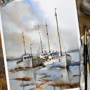 May include: A watercolor painting on paper depicting two white fishing boats moored in shallow water under a cloudy sky. The vessels feature tall masts and weathered hulls, with soft reflections visible in the water below. The artist signature is visible.