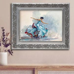 May include: Watercolor painting of a dancer in a flowing blue dress with red accents, framed in a silver ornate frame. The artwork captures the dancer mid-motion, with arms outstretched. The background features soft, watercolor washes.