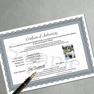 May include: A certificate of authenticity for a watercolor painting by Joseph R. Schaub. The certificate includes the title "Stonebank Cottage", painting size 11 x 15 inches, and the year 2025. A pen rests on the certificate.