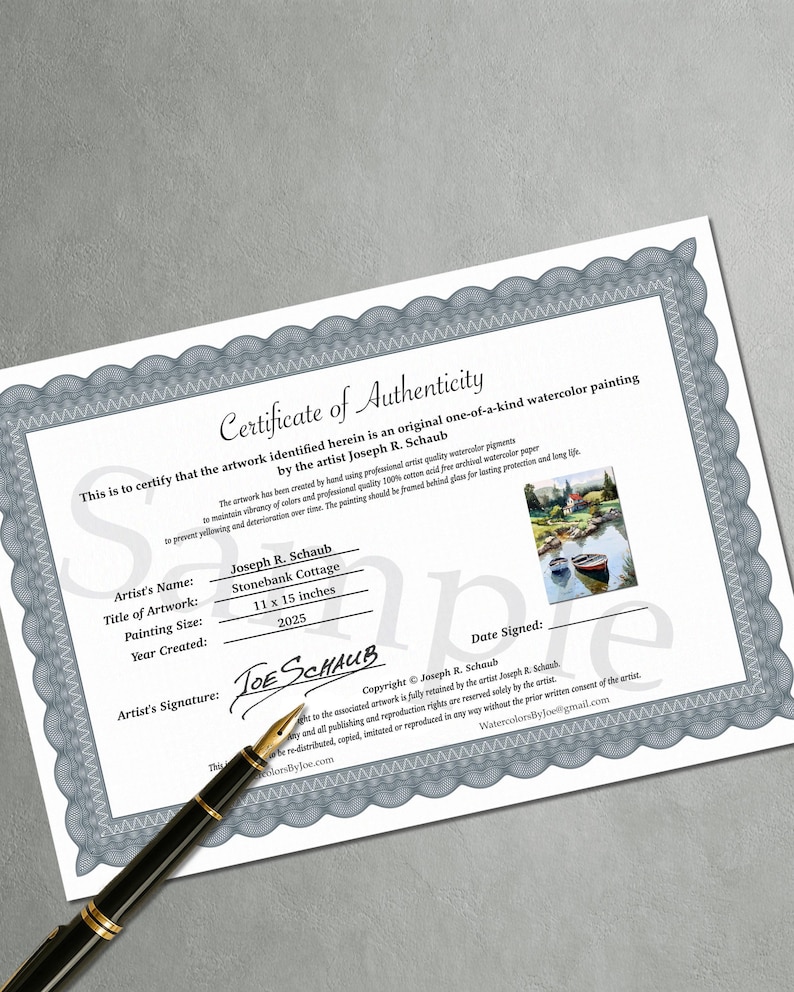 May include: A certificate of authenticity for a watercolor painting by Joseph R. Schaub. The certificate includes the title "Stonebank Cottage", painting size 11 x 15 inches, and the year 2025. A pen rests on the certificate.