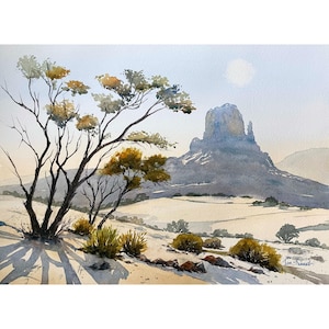 May include: Watercolor landscape painting depicting a desert scene. A large, gray mountain rises in the background under a pale sun. In the foreground, a tree with yellow and green leaves casts a long shadow over the sandy ground.