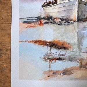 May include: A watercolor painting depicting a white fishing boat docked near a shoreline with muted gray, blue, and earthy brown tones. The artwork features a soft, atmospheric reflection on the water and includes the signature Joe Schaub in ink.