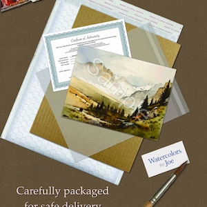 May include: A watercolor landscape painting of mountains and pine trees, a certificate of authenticity, a small business card reading Watercolors By Joe, a paintbrush, and a paint palette, all arranged with protective packaging materials.
