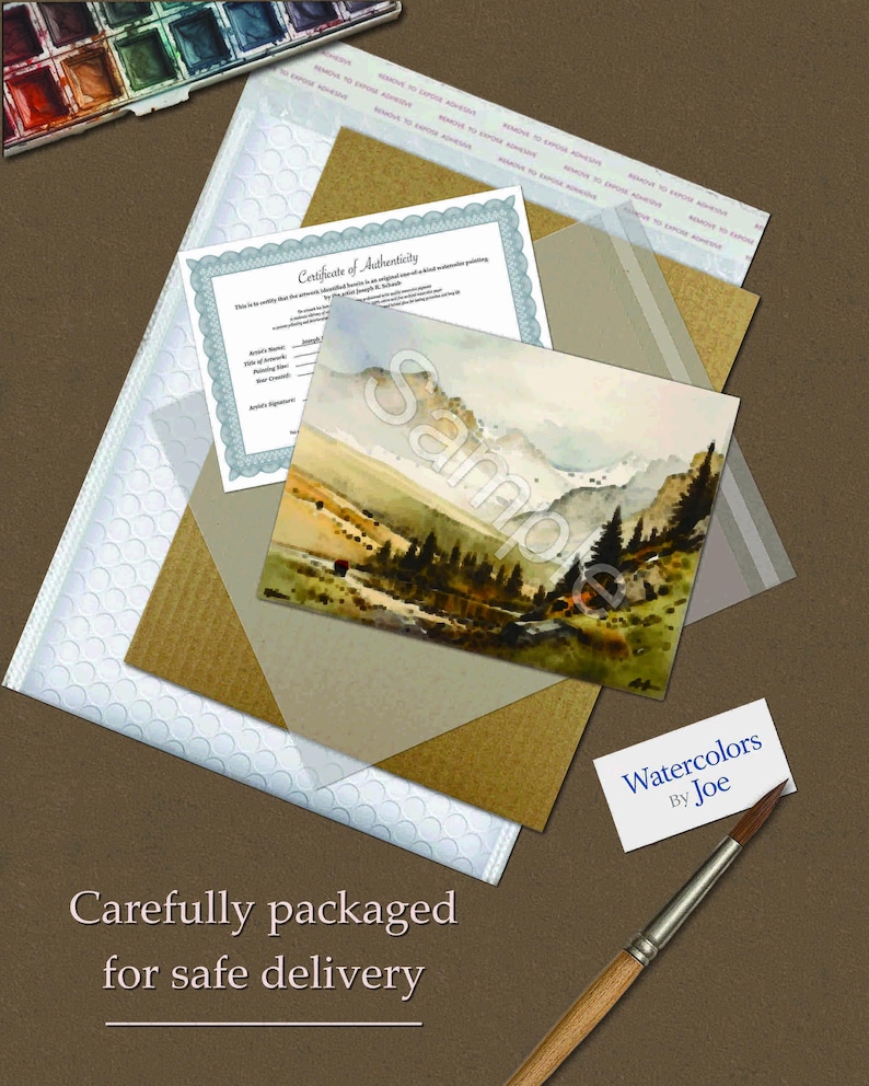May include: A watercolor landscape painting of mountains and pine trees, a certificate of authenticity, a small business card reading Watercolors By Joe, a paintbrush, and a paint palette, all arranged with protective packaging materials.