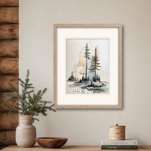 May include: A framed watercolor painting depicting a forest scene with tall pine trees in shades of green, brown, and muted orange, reflected in a calm body of water. The artwork is enclosed in a light-toned wooden frame with a white mat border.