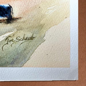 May include: Watercolor painting with a landscape theme. The artwork features a signature in the lower left corner, "Joe Schaub". The painting has a soft color palette with shades of blue, beige, and green.