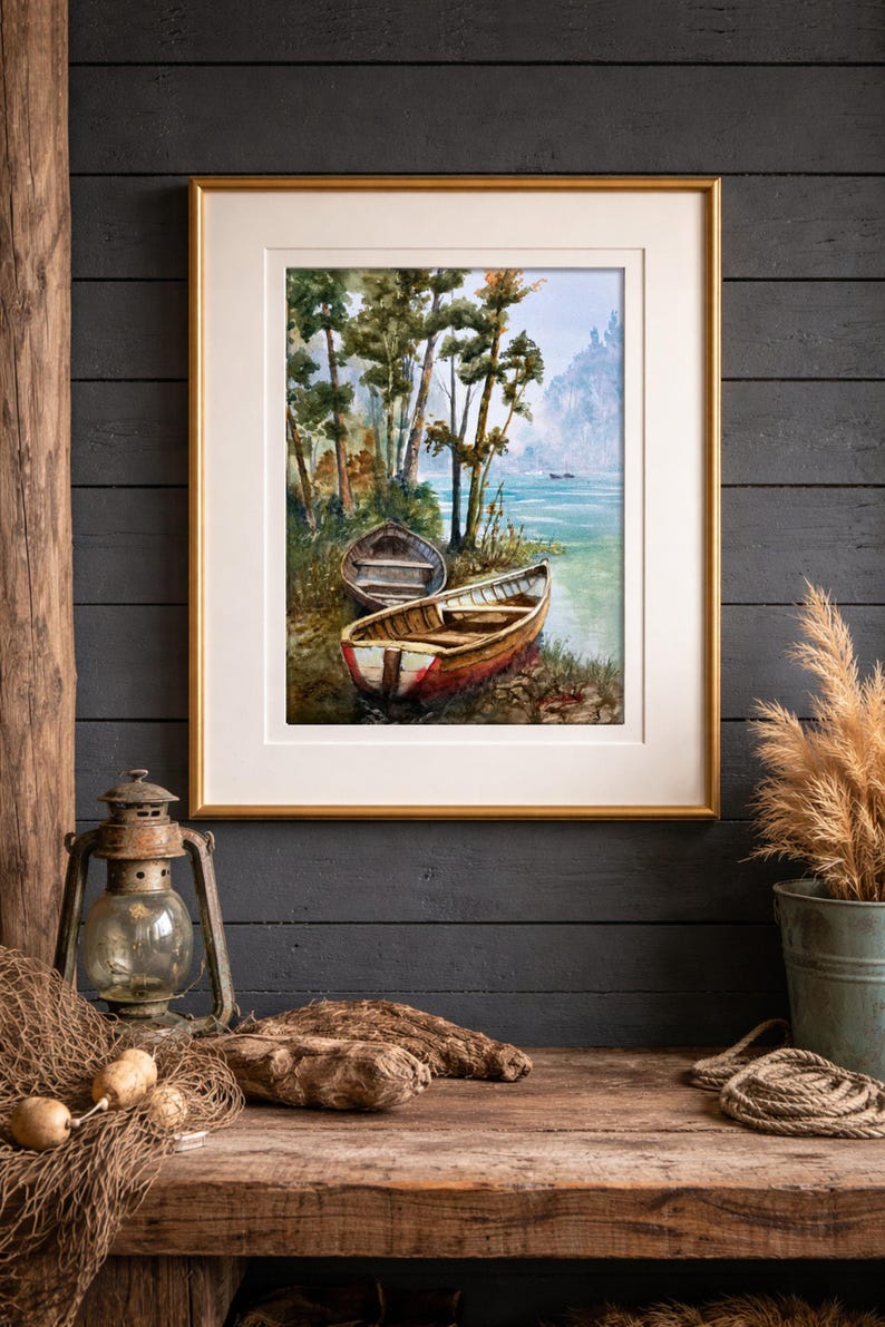Op de afbeelding: Een ingelijste aquarel van twee boten aan een oever met bomen. De schildering zit in een gouden lijst en wordt tentoongesteld op een rustiek houten oppervlak. Een vintage lantaarn en visnet staan op de voorgrond.