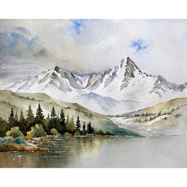 May include: A watercolor painting depicting a serene mountain landscape with snow-capped peaks rising above a calm lake. Dark green pine trees line the shore in the foreground, while soft blue and gray clouds drift across the sky above the mountains.
