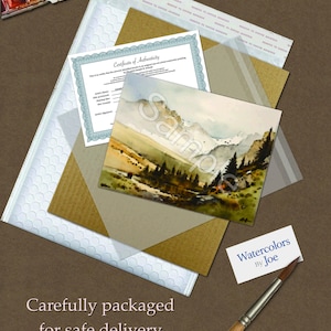 May include: A watercolor landscape painting of mountains and trees with a Certificate of Authenticity, a white bubble mailer, a brown cardboard backing, a small business card reading Watercolors by Joe, and a wooden paintbrush with a brown handle.