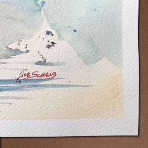 May include: Watercolor painting with soft blue, gray, and beige hues. The artwork features abstract shapes and splatters, with the artist's signature, "Joe Schaub," in red ink at the bottom. The painting is on textured watercolor paper.