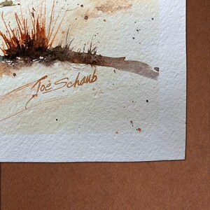 K&ouml;nnte beinhalten: Aquarellmalerei mit einer Nahaufnahme von trockenem Gras in Braun- und Oranget&ouml;nen. Das Kunstwerk hat ein weiches, strukturiertes Aussehen mit subtilen Farbspritzern. Die Signatur des K&uuml;nstlers, "Joe Schaub", ist unten links zu sehen.