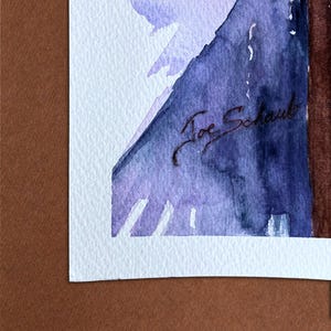 May include: Watercolor painting with shades of purple and blue, signed "Joe Schaub". The artwork is mounted on a white mat and set against a brown background. The painting features abstract shapes and soft color transitions.