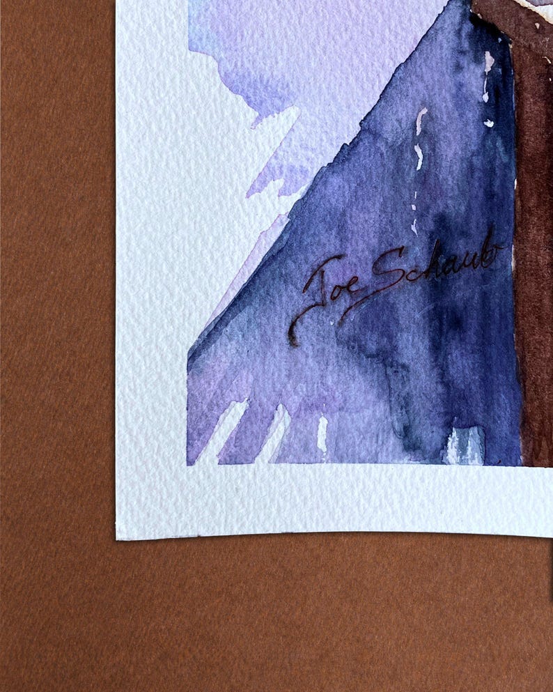 May include: Watercolor painting with shades of purple and blue, signed "Joe Schaub". The artwork is mounted on a white mat and set against a brown background. The painting features abstract shapes and soft color transitions.