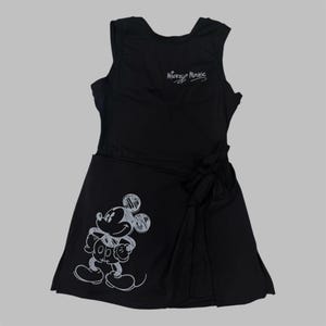 May include: Black sleeveless dress featuring a white sketch of Mickey Mouse on the front and the text "Mickey Mouse" in white script. The dress has a wrap-style skirt with a bow detail at the waist.