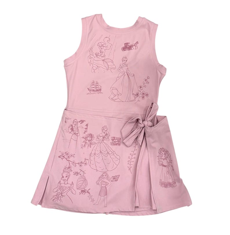 May include: Pink sleeveless dress with a wrap skirt and bow. The dress features line drawings of various princesses and related imagery. The illustrations are in a darker shade of pink. The dress is made of a soft, lightweight fabric.