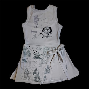 May include: A two-piece outfit featuring Star Wars characters. The top is a sleeveless tank with illustrations of Darth Vader and Chewbacca. The skirt is a wrap style with images of Yoda, R2-D2, and other characters. The outfit is light beige with black line art.