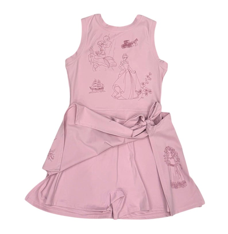 May include: A light pink romper with a sleeveless top and attached shorts, featuring a wrap-around waist tie. The top is adorned with line drawings of fairytale characters, including a princess and a ship.