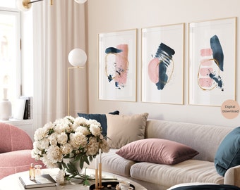 May include: Three abstract art prints with a pink and blue colour scheme. The prints feature gold accents and are framed in gold. The prints are hanging on a wall in a living room setting.