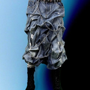 May include: A blue denim skirt with a distinctive layered design, featuring distressed details and a silver chain. The skirt is worn with a black belt and chunky black boots. The background fades from blue to black.